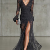 Vestido longo em renda cinza escuro, com babados, transparente, com mangas longas e fenda lateral.