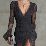 Vestido longo em renda cinza escuro, com babados, transparente, com mangas longas e fenda lateral.