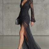 Vestido longo em renda cinza escuro, com babados, transparente, com mangas longas e fenda lateral.